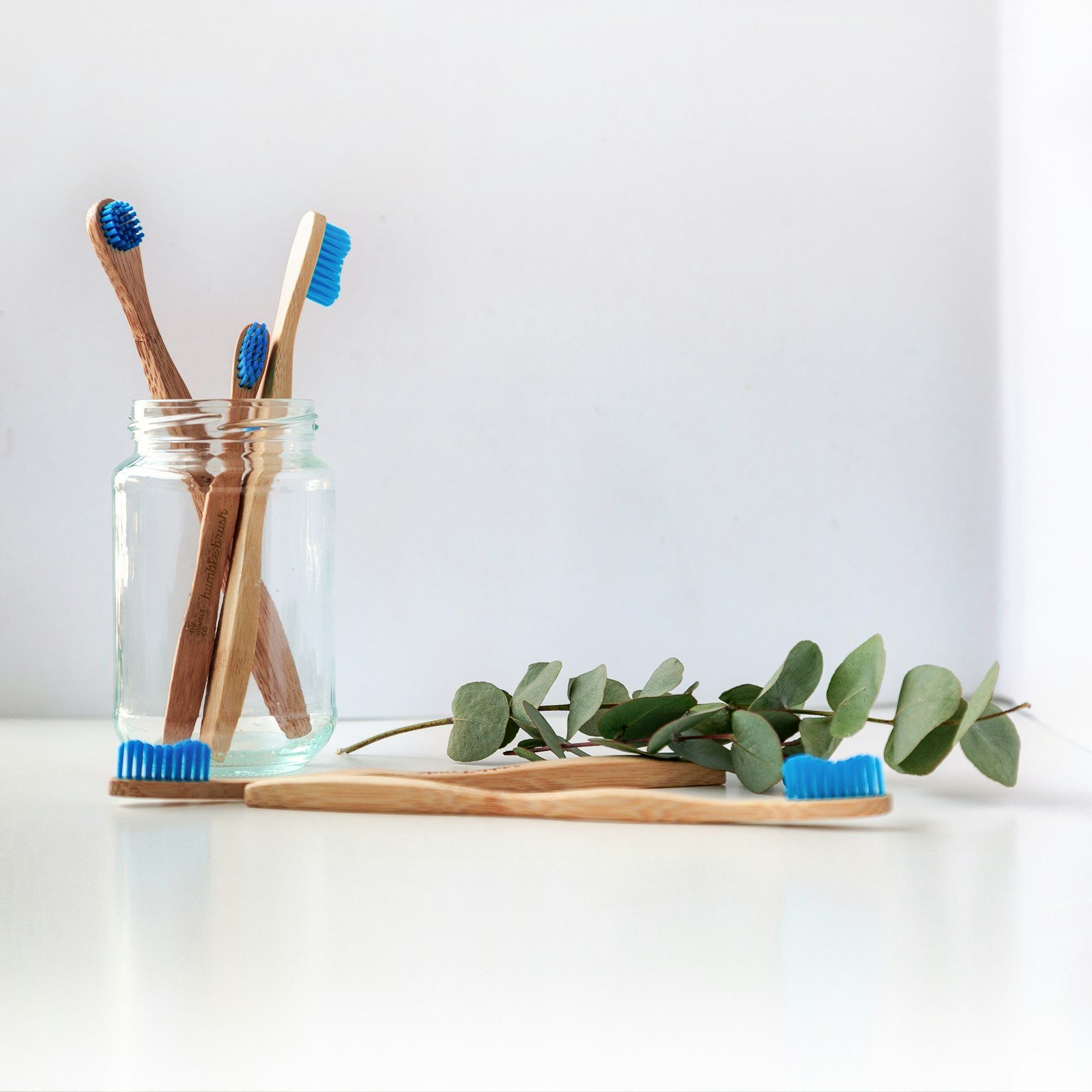 A toothbrush and eucalyptus arranged on a wooden surface